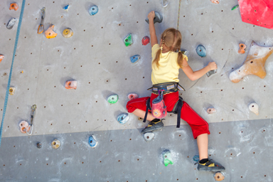 Little girl climbing an indoor rock wall