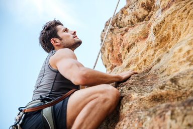 Young man climbing a steep mountain